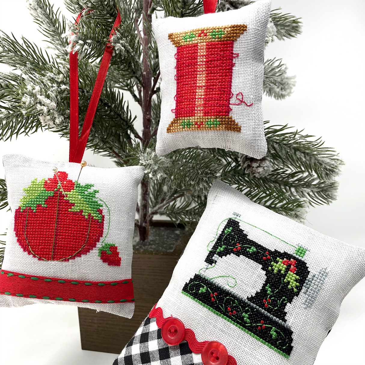 Three ornaments with pin cushion, thread and sewing machine