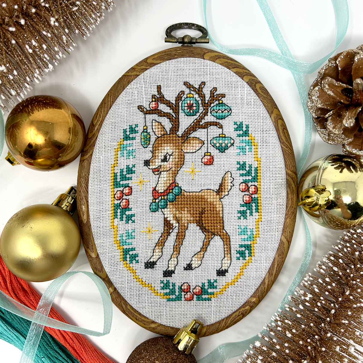 VIntage style deer with ornaments hanging on antlers and ribbon and christmas balls around it. 