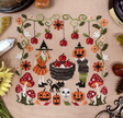 seasonal sampler with some cute characters about to bob for apples in a barrel, with a black cat, pumpkins, and vintage-inspired border.&nbsp;