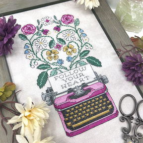 Typewriter with flowers coming out with the words “follow your heart”