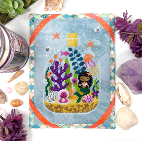 Mermaid, coral and shells in a glass bottle