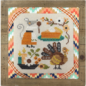 Cross-stitched design with a turkey, pie, and autumn elements on a wooden frame.