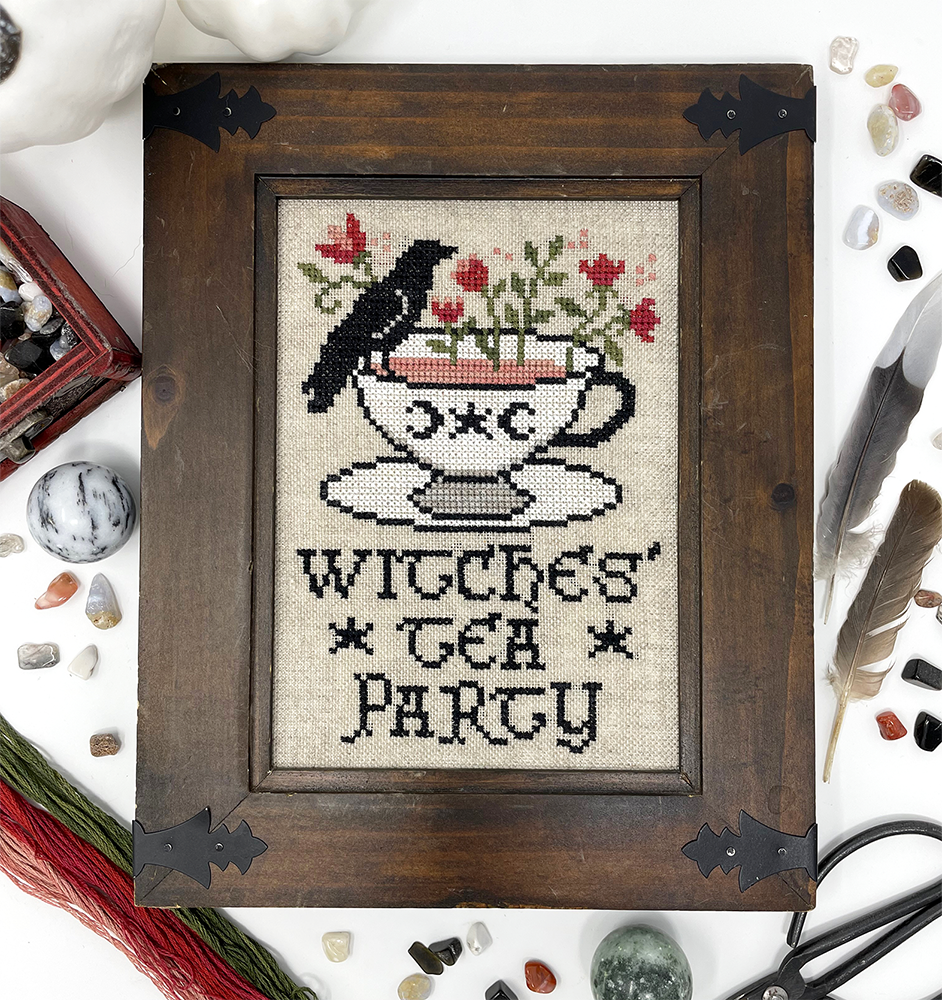 Crow sitting on tea cup with words “witches’ tea party”